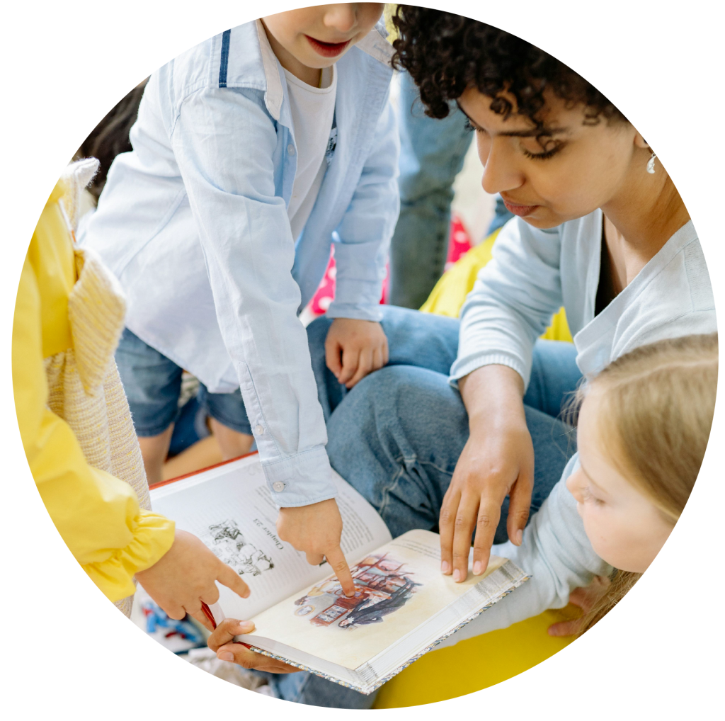 teacher looking at book with children